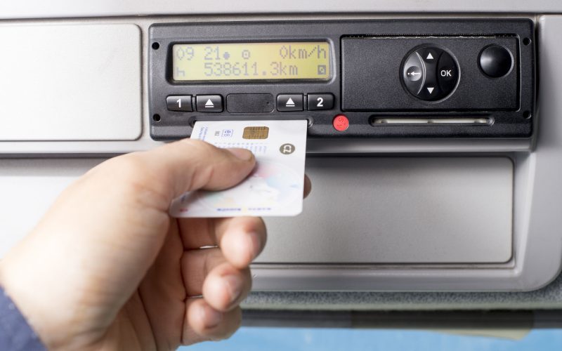 Digital tachograph and drivers hand inserting the digital card.